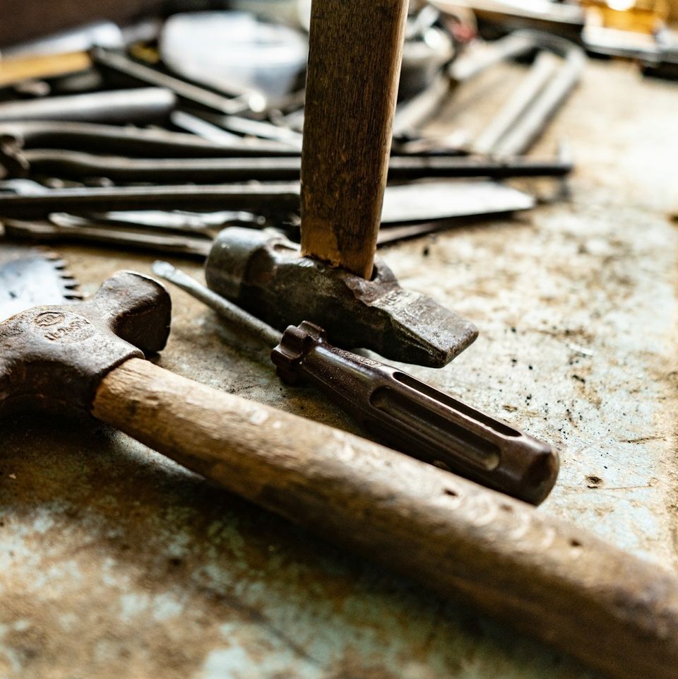 Claw hammer, saw and nails on a worn workbench