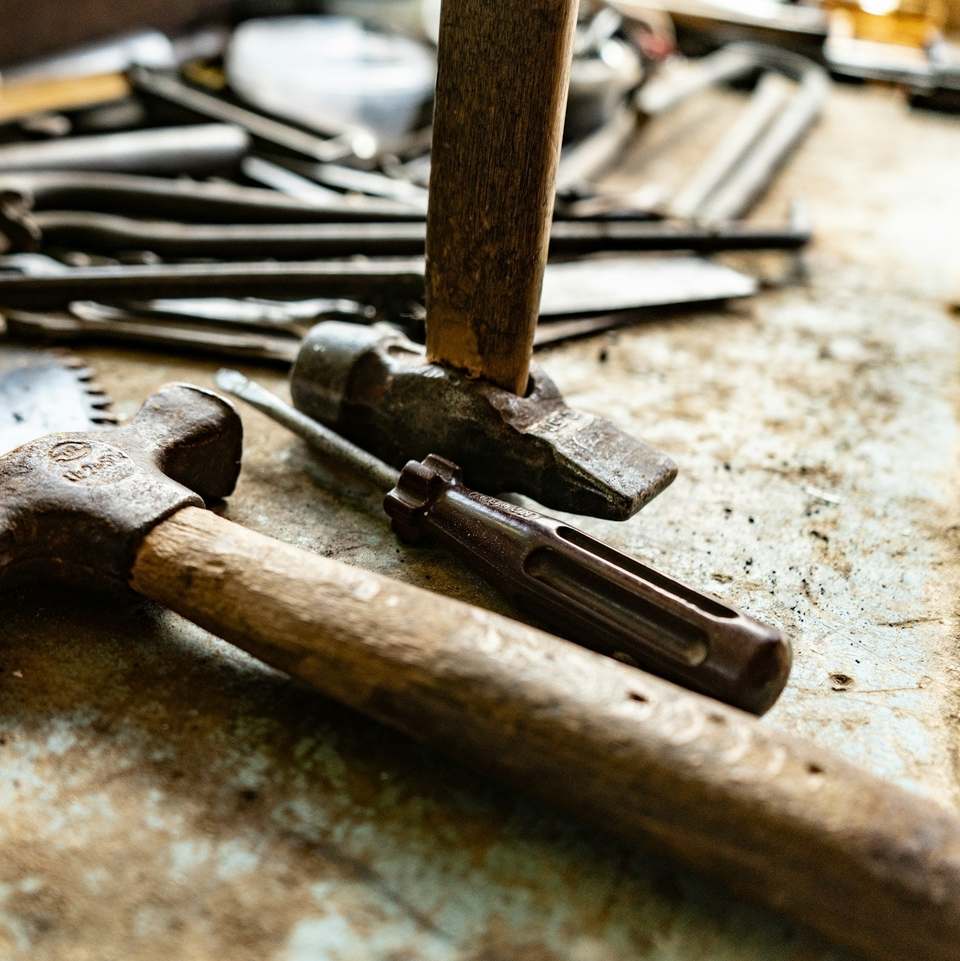 Claw hammer, saw and nails on a worn workbench