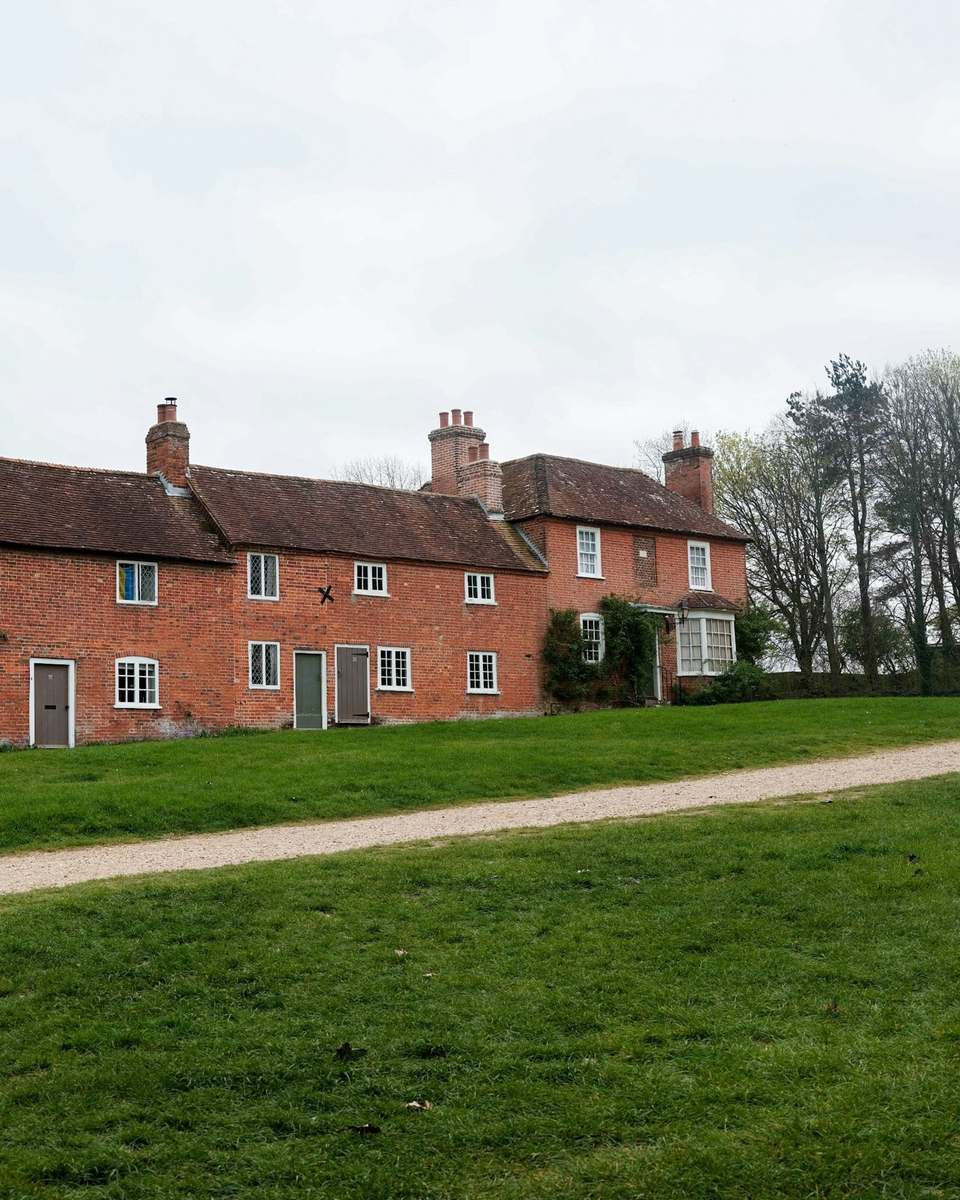 Row of red brick houses with white windows, green doors and tall chimneys
