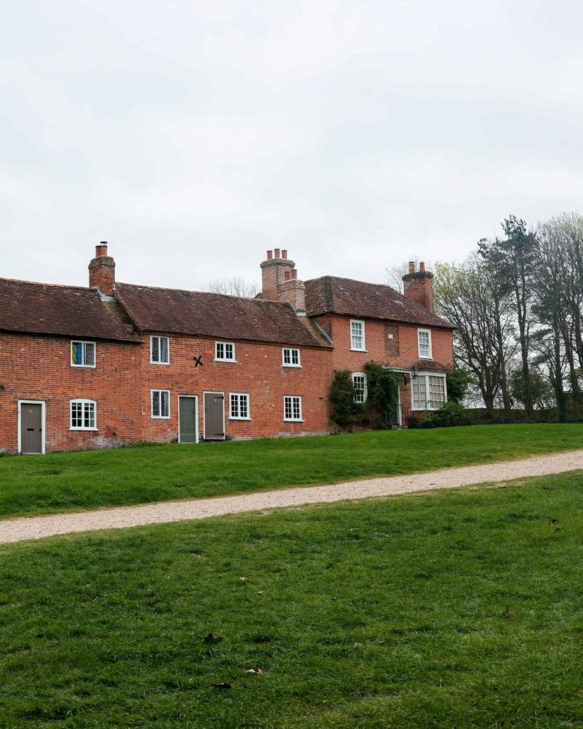 Row of red brick houses with white windows, green doors and tall chimneys