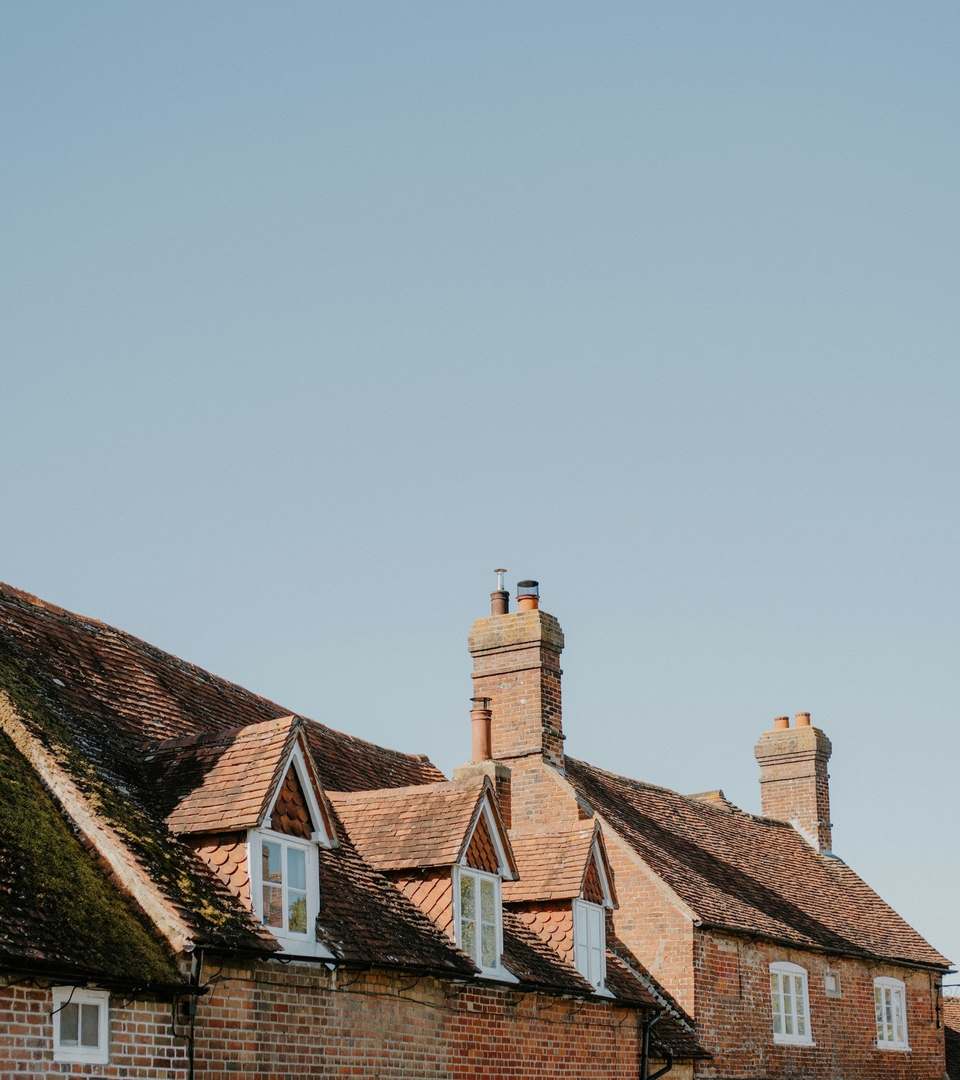 Brick houses with tiled roofs and chimney stacks against a clear sky