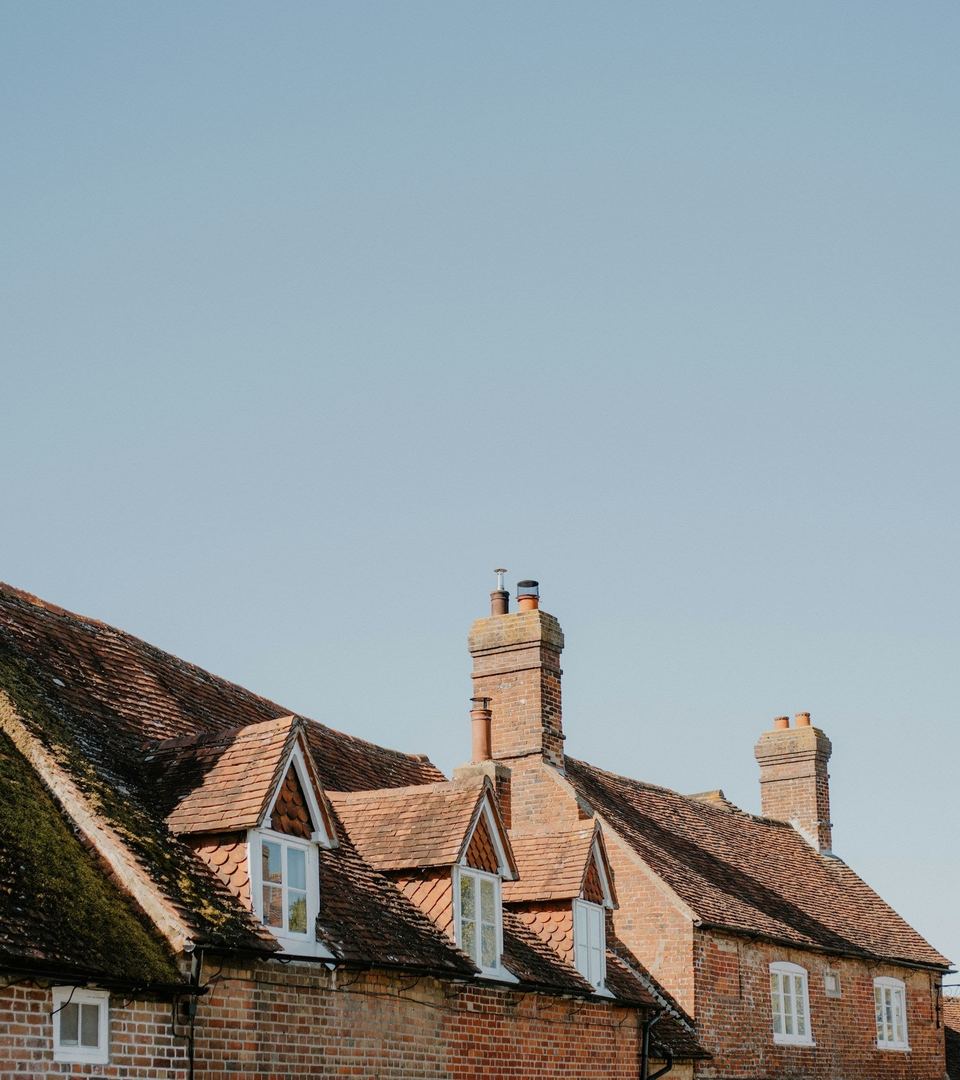 Brick houses with tiled roofs and chimney stacks against a clear sky